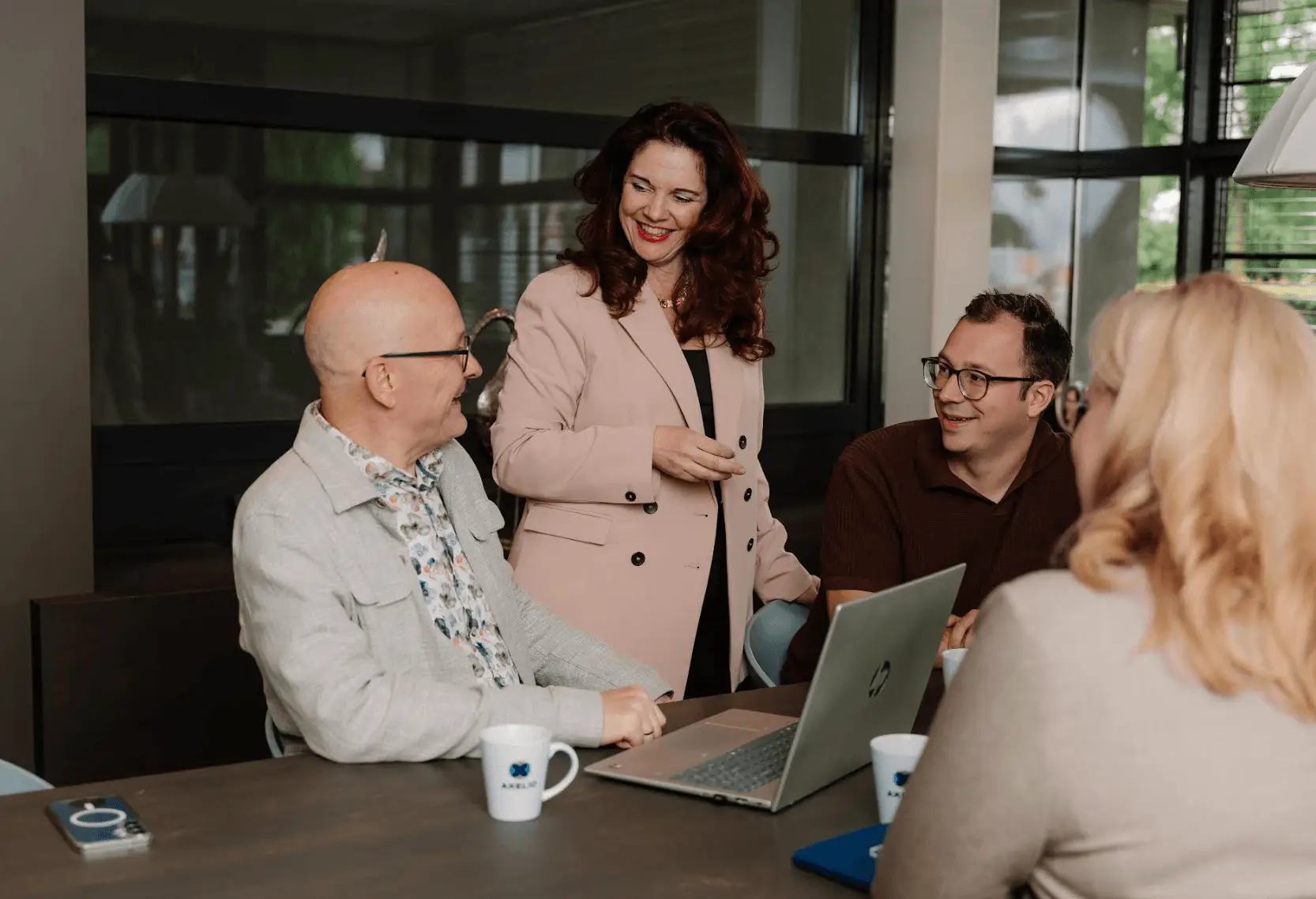 Twee mannelijke en twee vrouwelijke collega's van verschillende leeftijden werken lachend in een kantoorruimte.