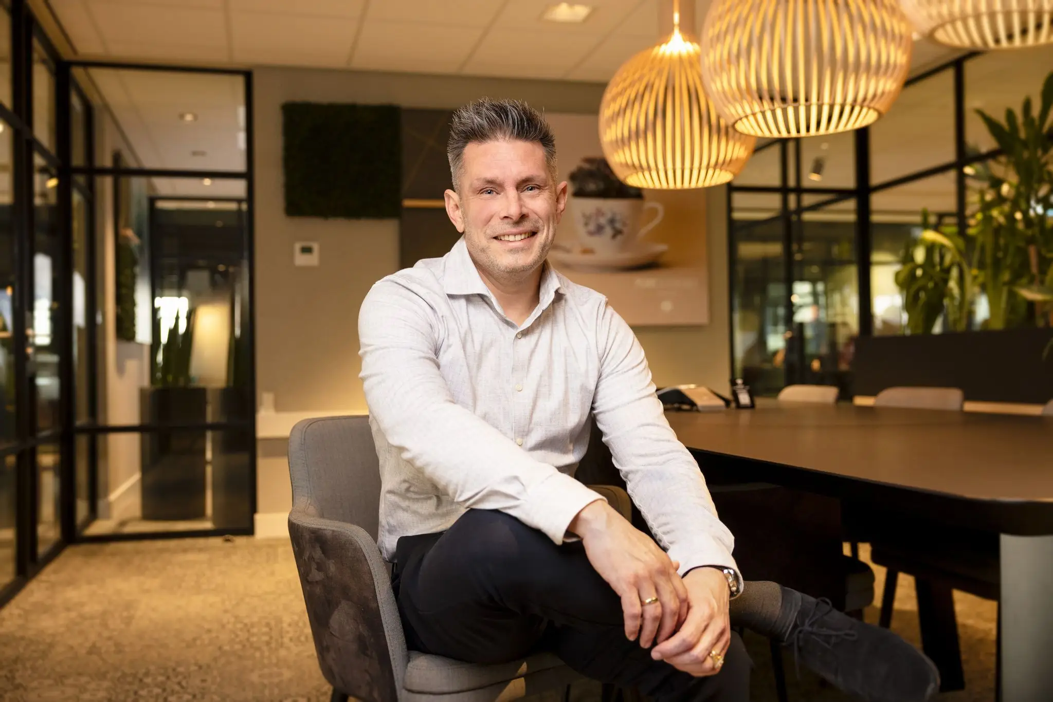 Richard Daniels zitten met de handen op zijn ben in een sfeervolle vergaderruimte