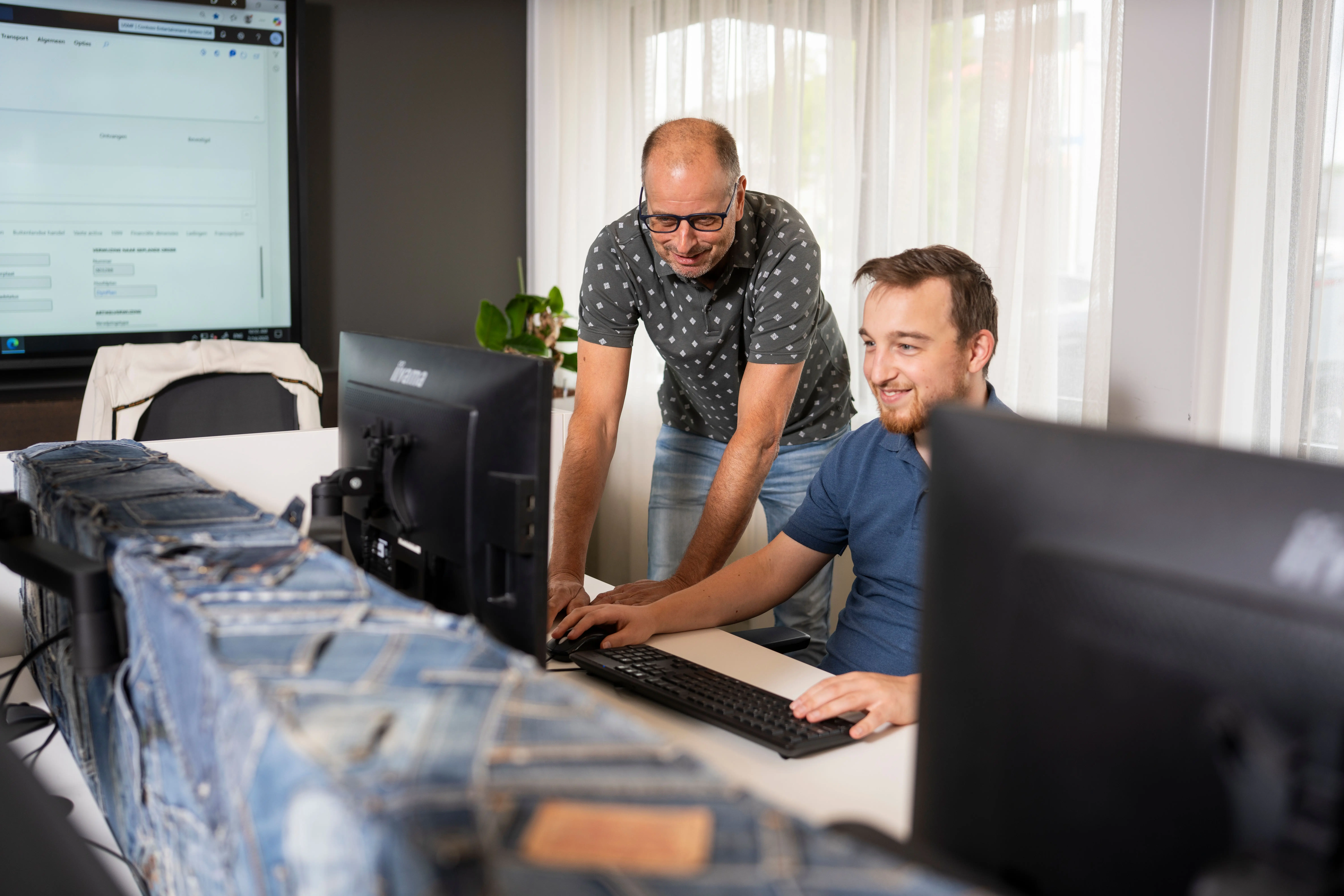 Twee collega's die met elkaar naar een computerscherm kijken