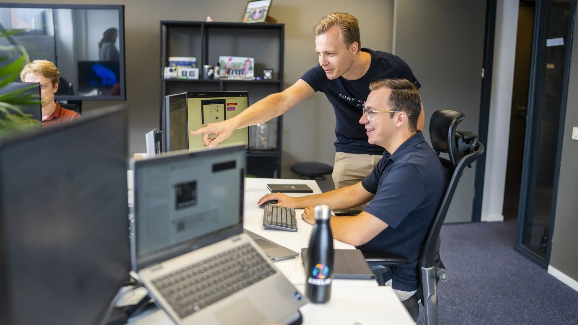 Twee jongens achter een computer waarbij er wordt gewezen op het scherm