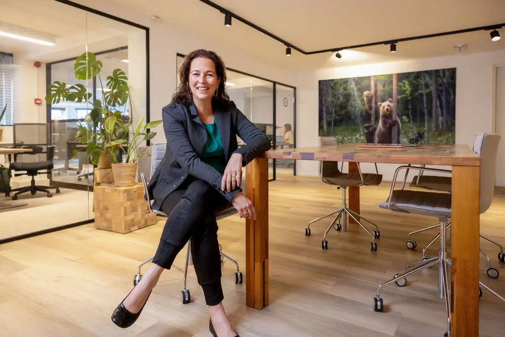 Vrouw zit op stoel en kijkt je lachend aan
