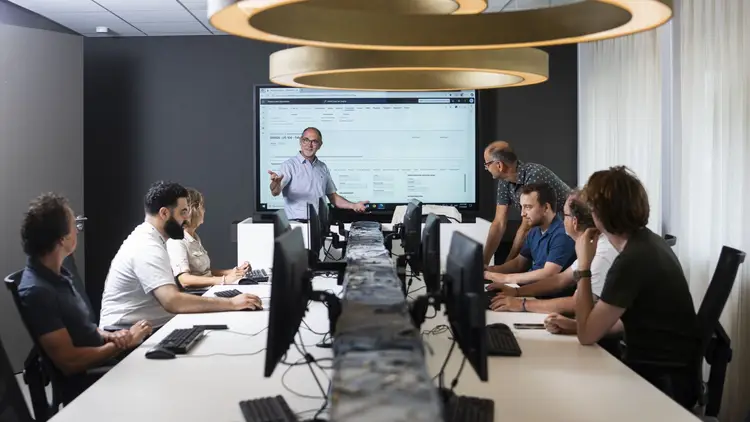 Een trainer die uitleg voor een groep mensen Axelio Academy