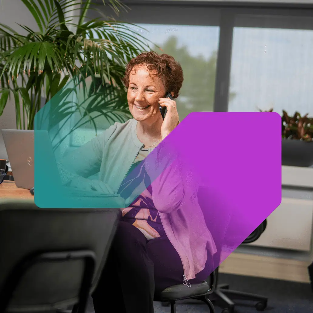Een oudere dame lachend en bellend aan een tafel 