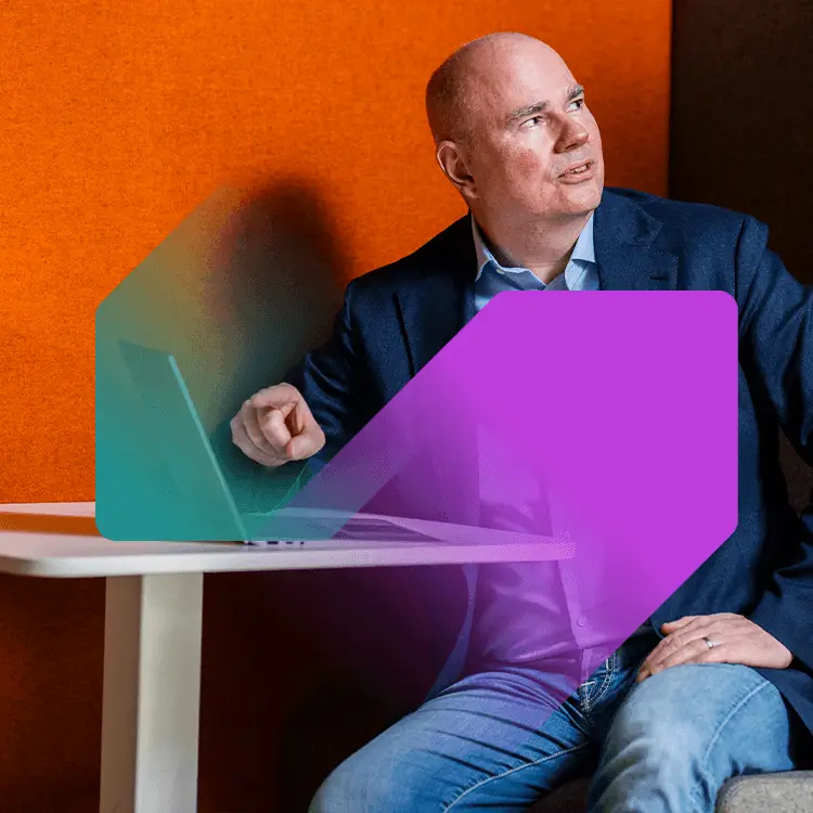 Een kale man wijzend naar een laptopscherm met oranje achtergrond