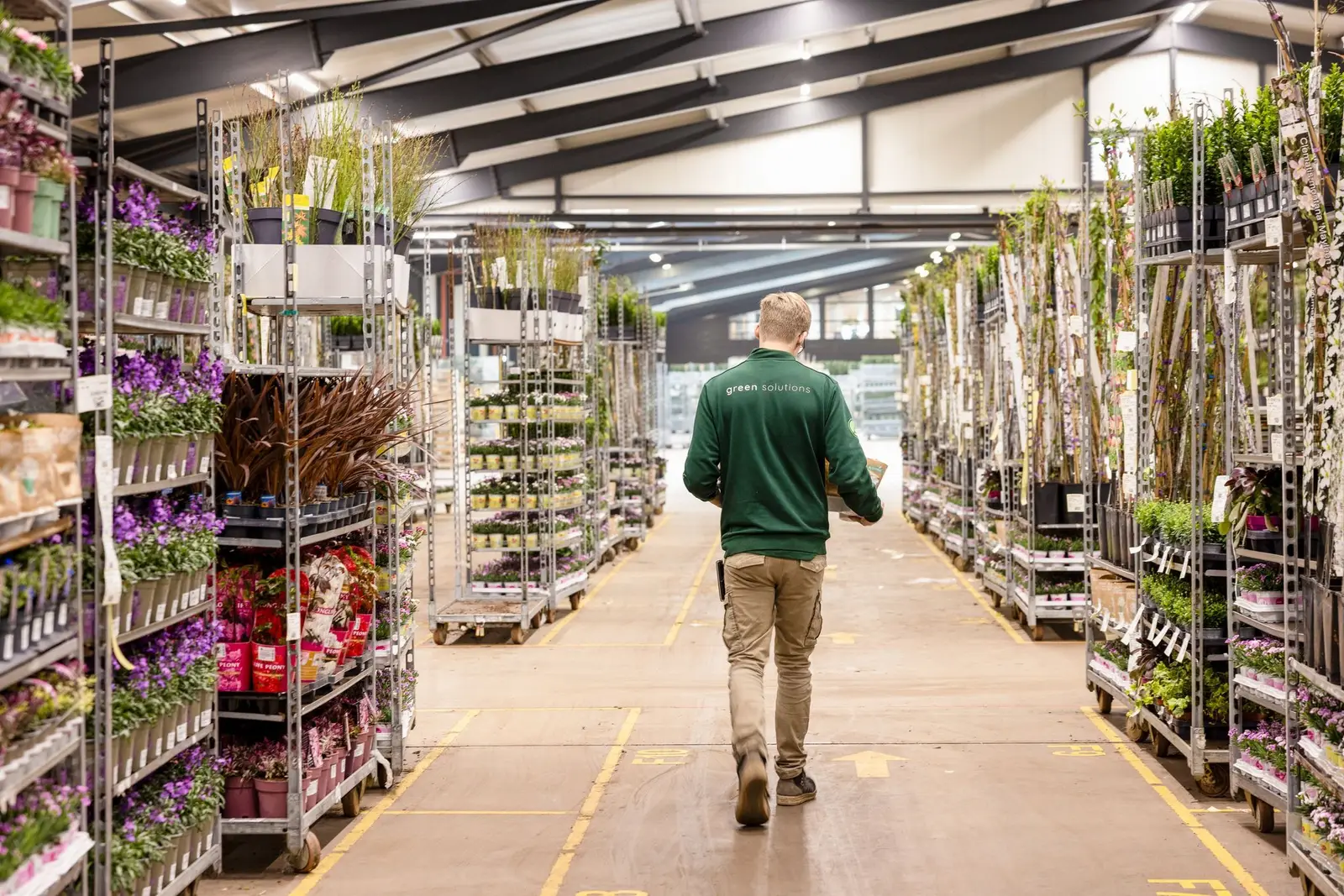 Een man lopen door een hal met karren met planten
